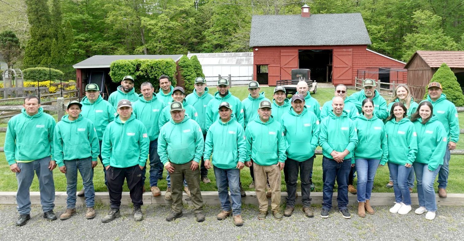 A large group of people wearing green shirts are posing for a picture