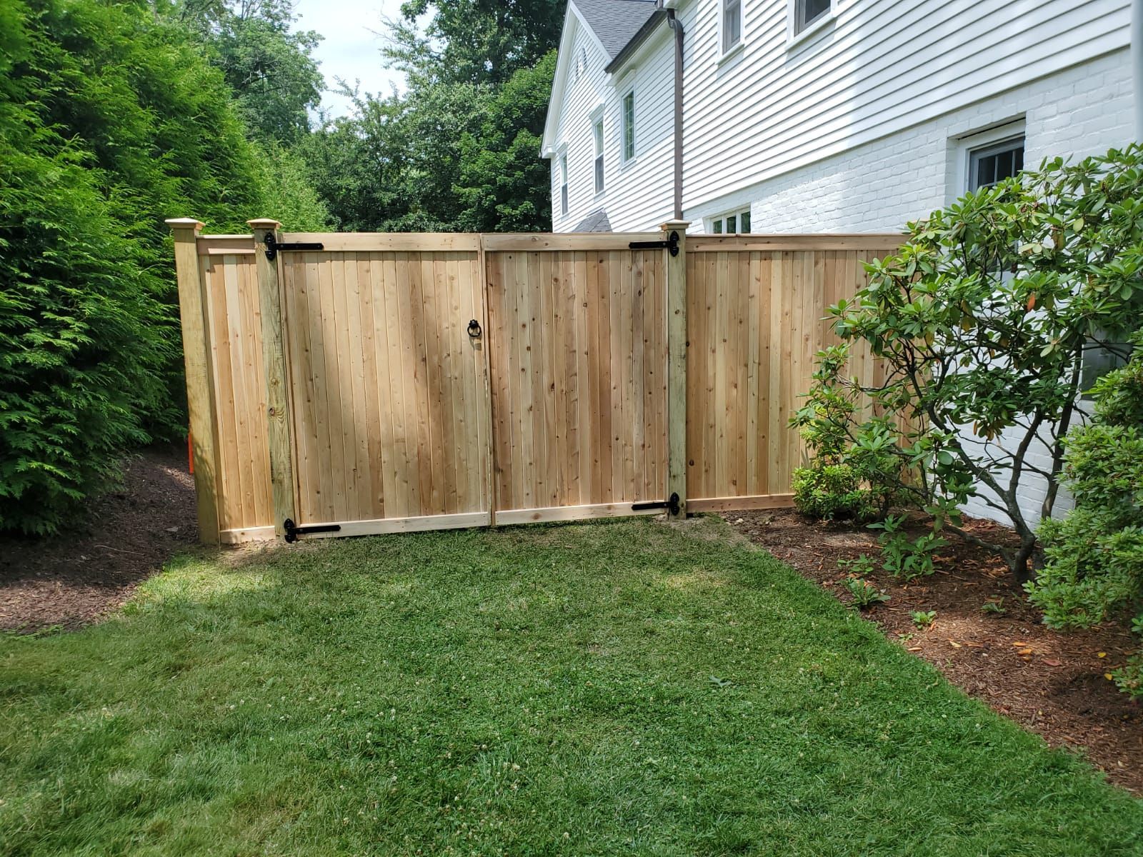 A wooden fence with a gate in the backyard of a house.