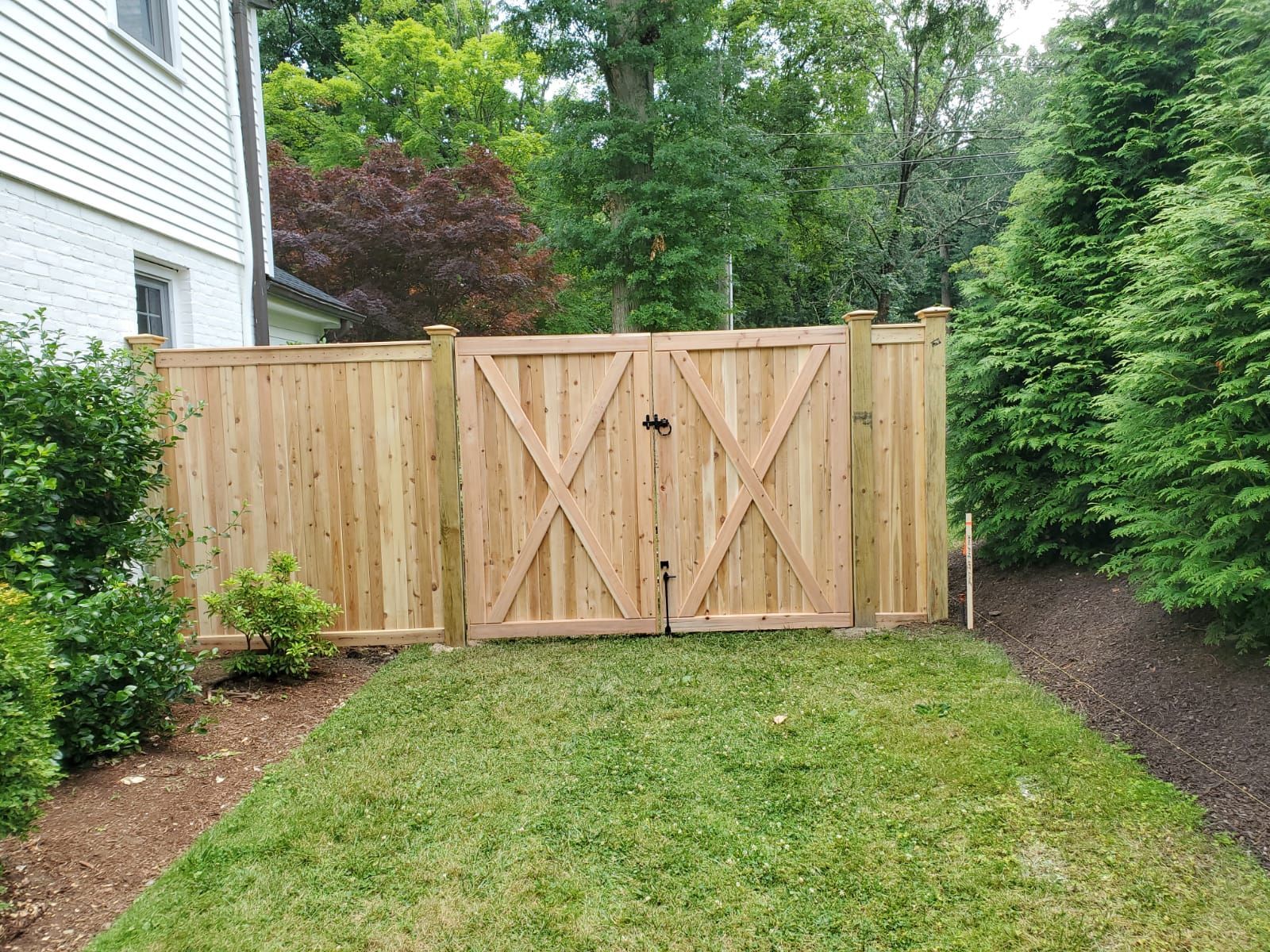 A wooden fence with a gate in the backyard of a house.