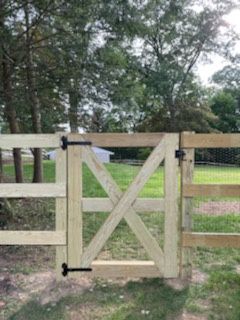 A wooden gate is sitting in the middle of a grassy field.