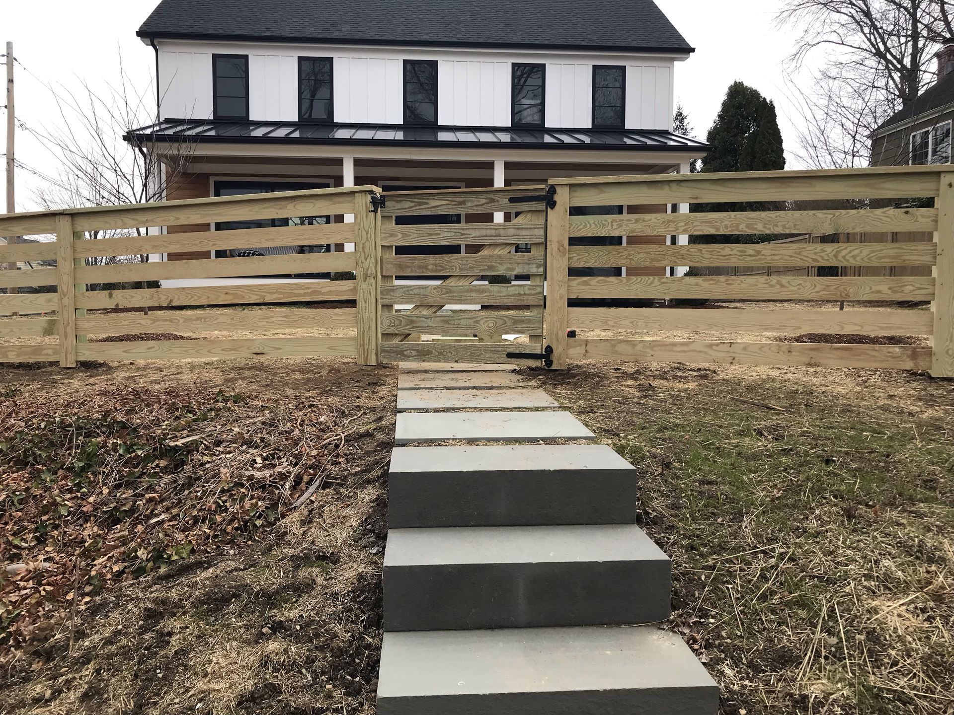 A wooden fence surrounds a house with stairs leading up to it.