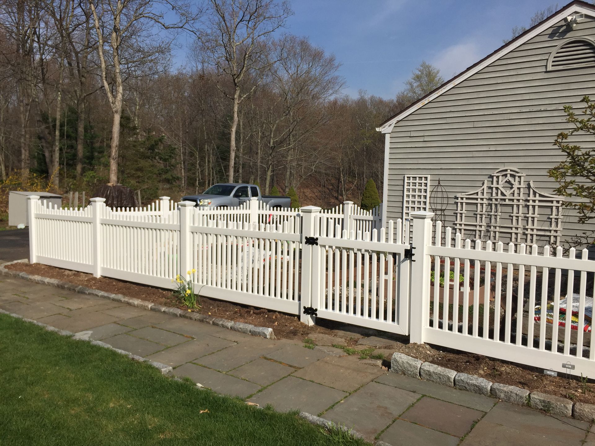 A white picket fence is in front of a house.
