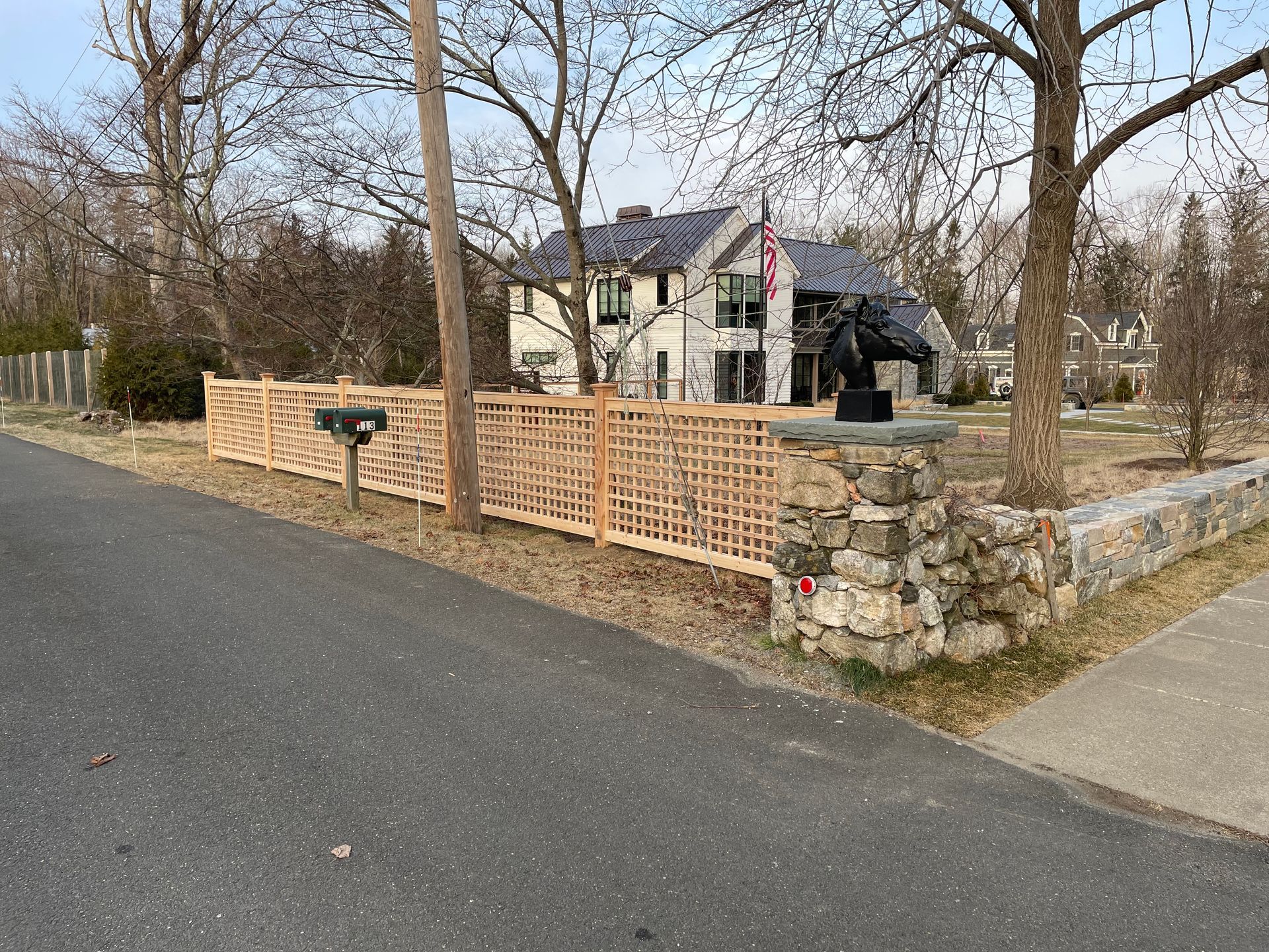 A wooden fence along the side of a road next to a house.