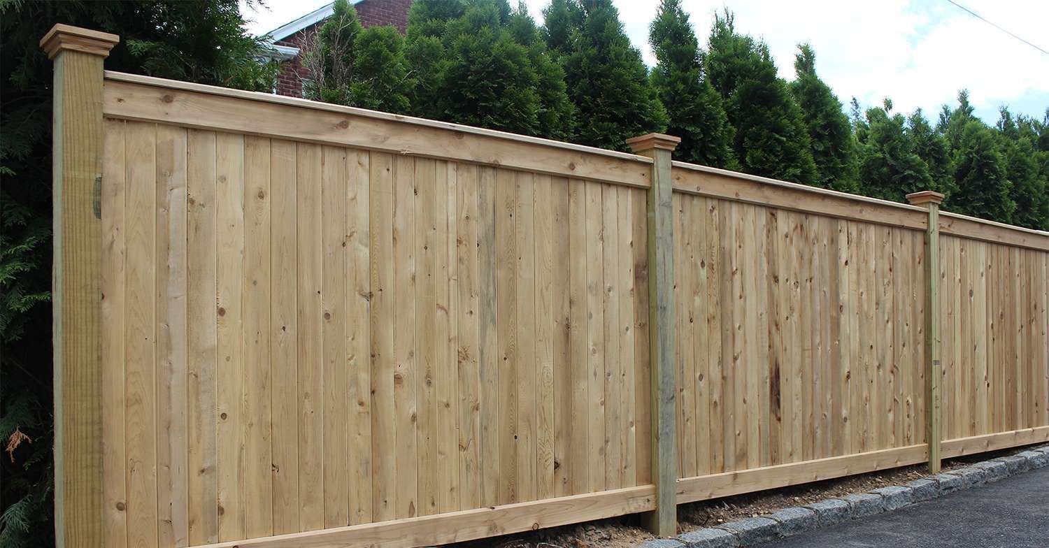A wooden fence is sitting on the side of a road.