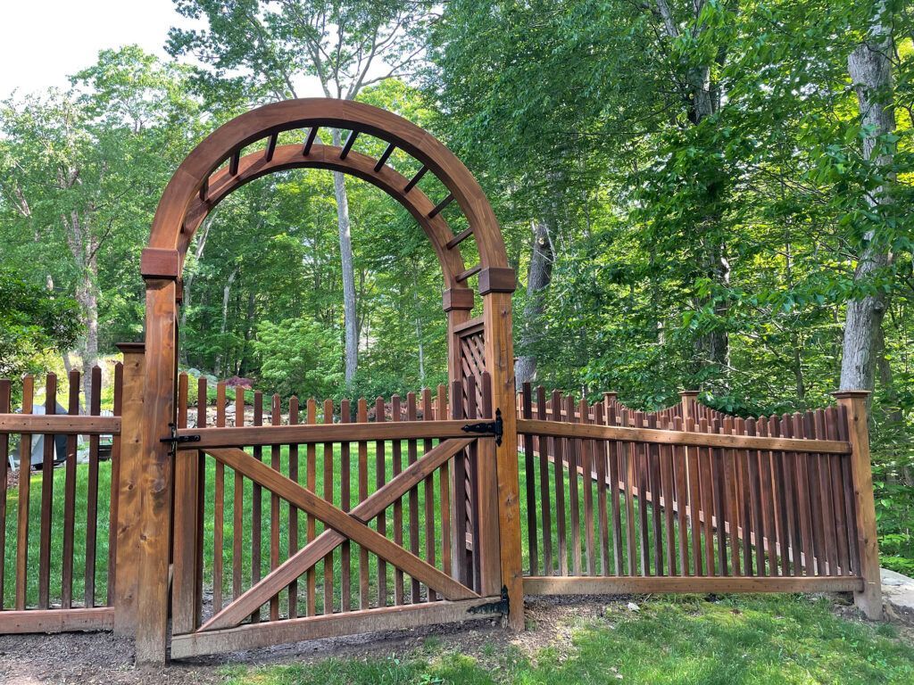 A wood fence with a gate and an arbor in the middle of it