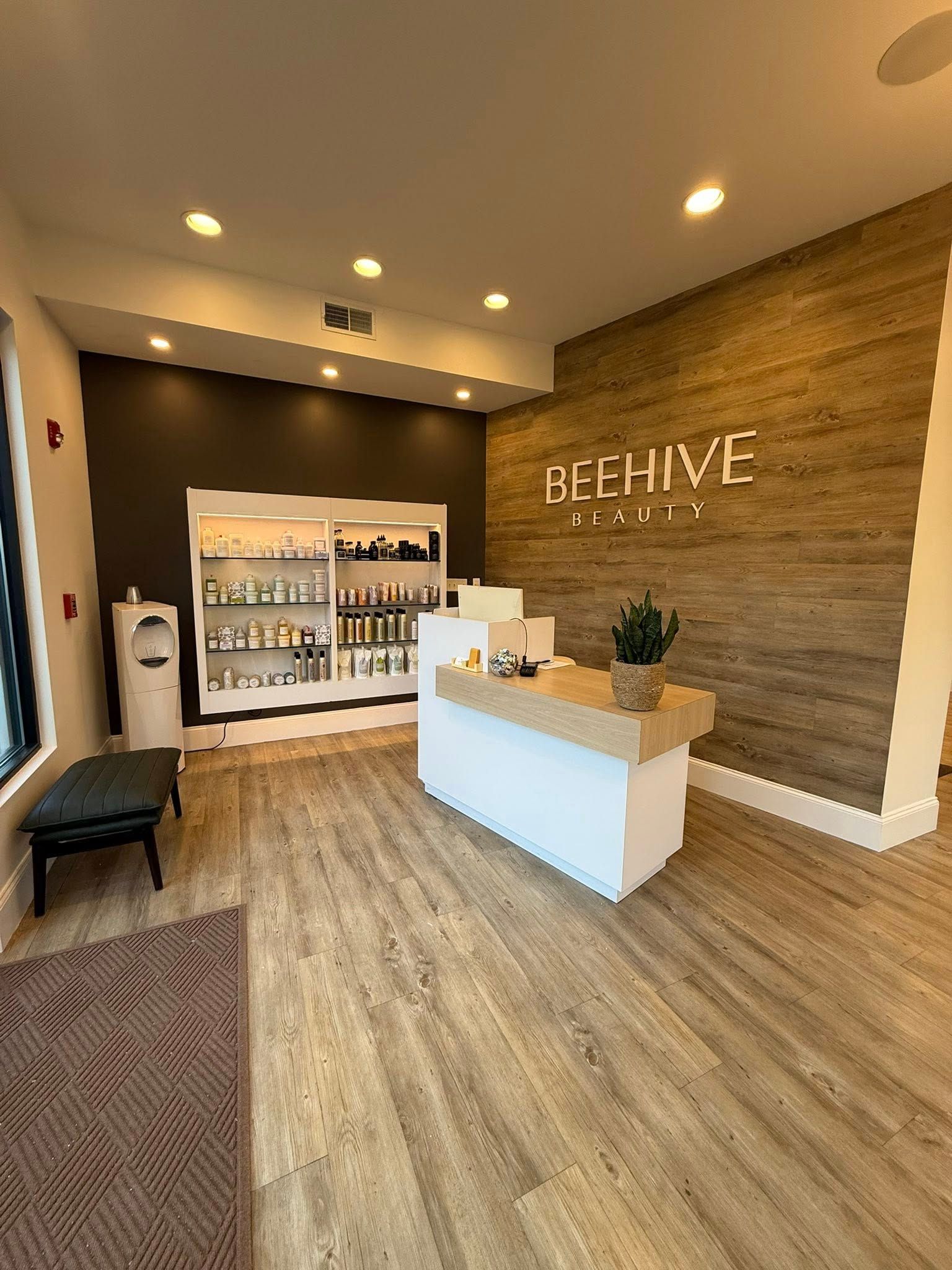 Modern lobby with wood floors, white reception desk, and “ARCHIVE” sign on textured wall.