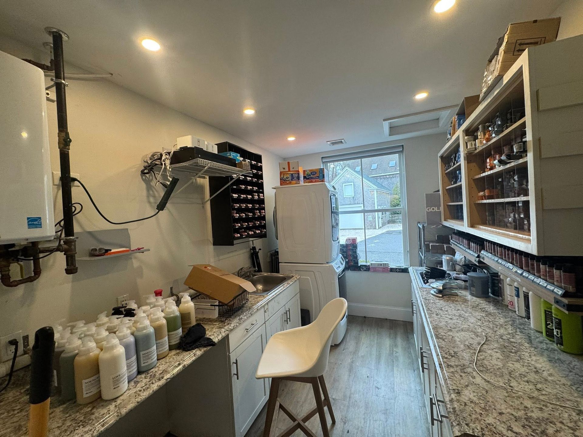 Narrow salon or spa workspace with product shelves, counter, chair, and window at the back