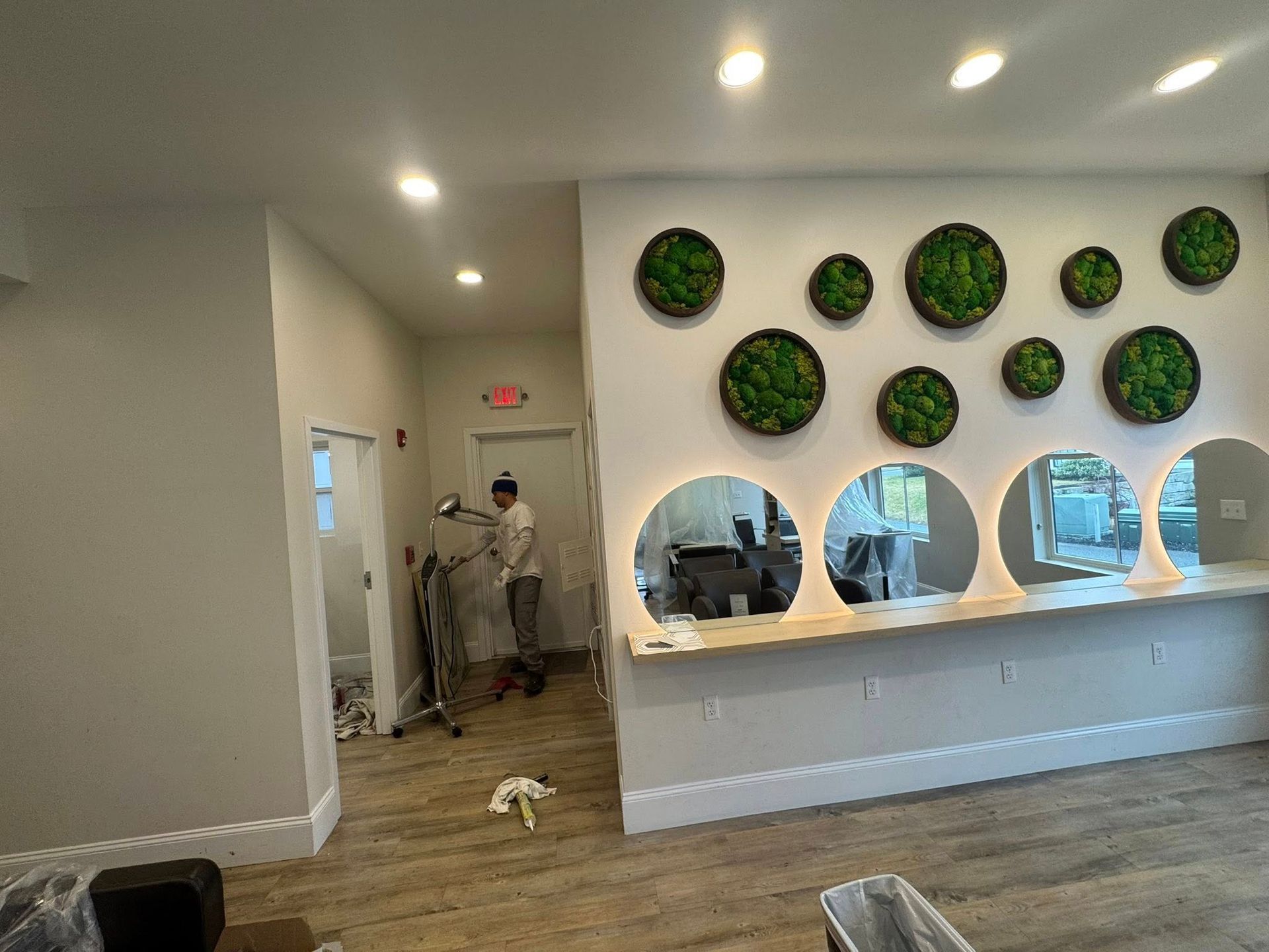 Modern lobby with round green wall art, white reception desk, and a person near the hallway.