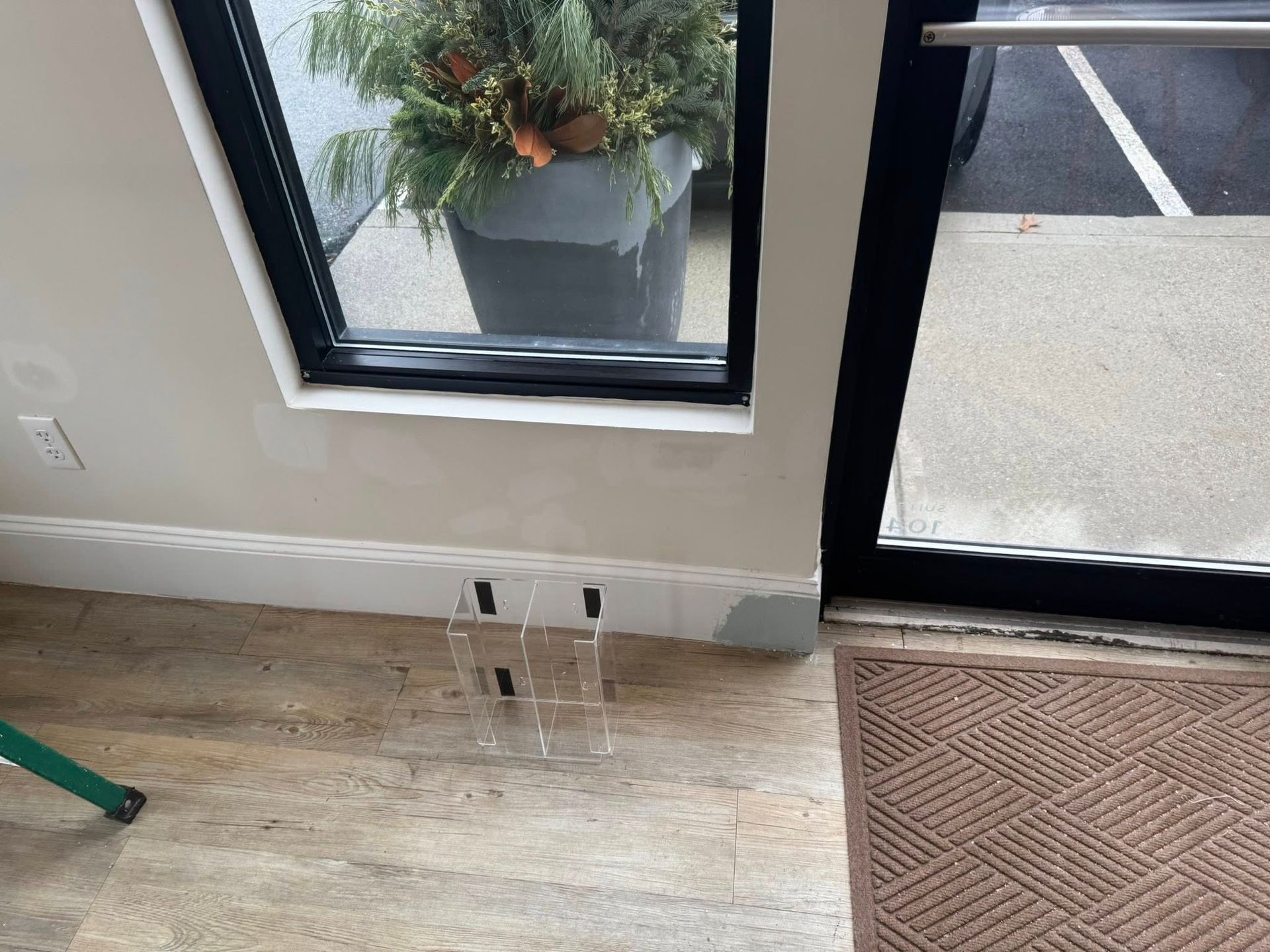 Small storefront interior with wood floor, window, glass door, and low wall outlets near the baseboard.