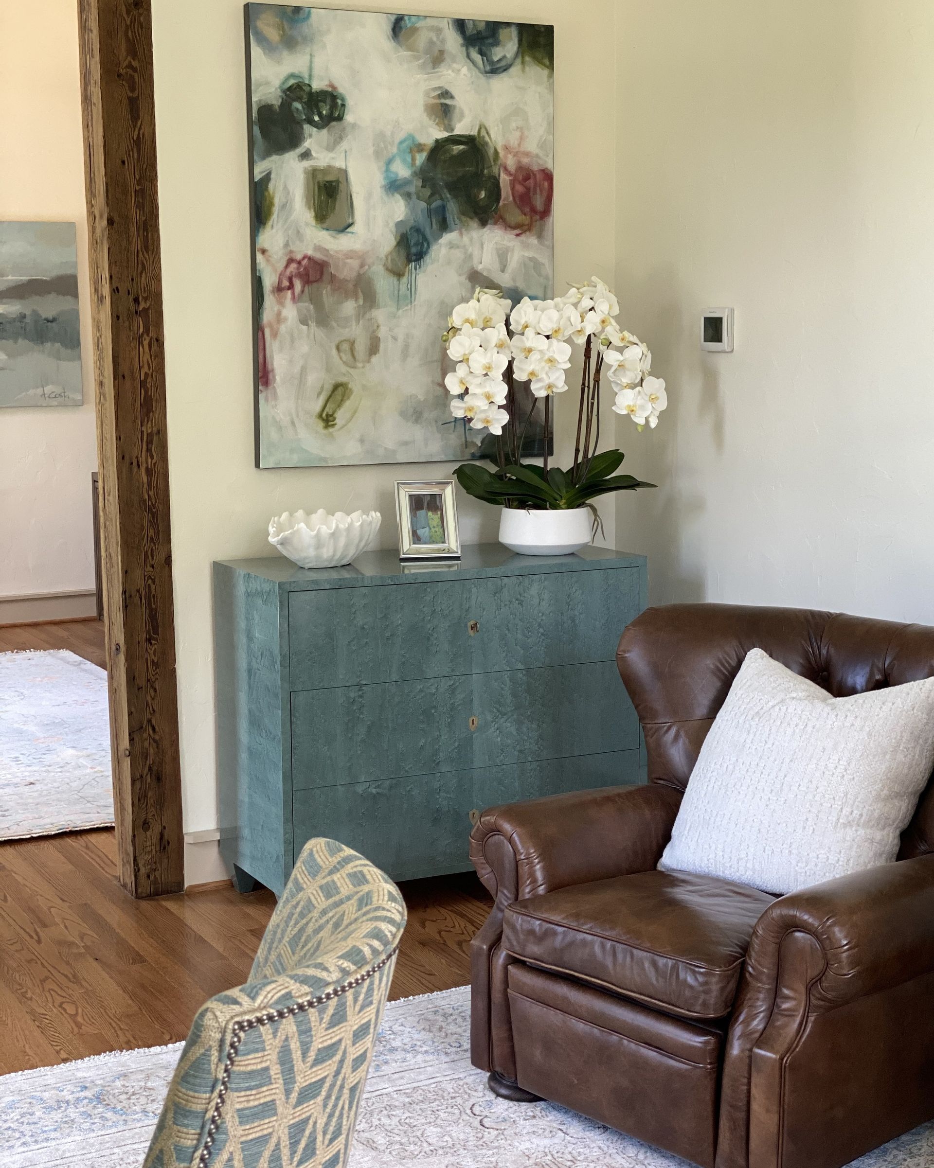 A living room with a chair and a painting on the wall