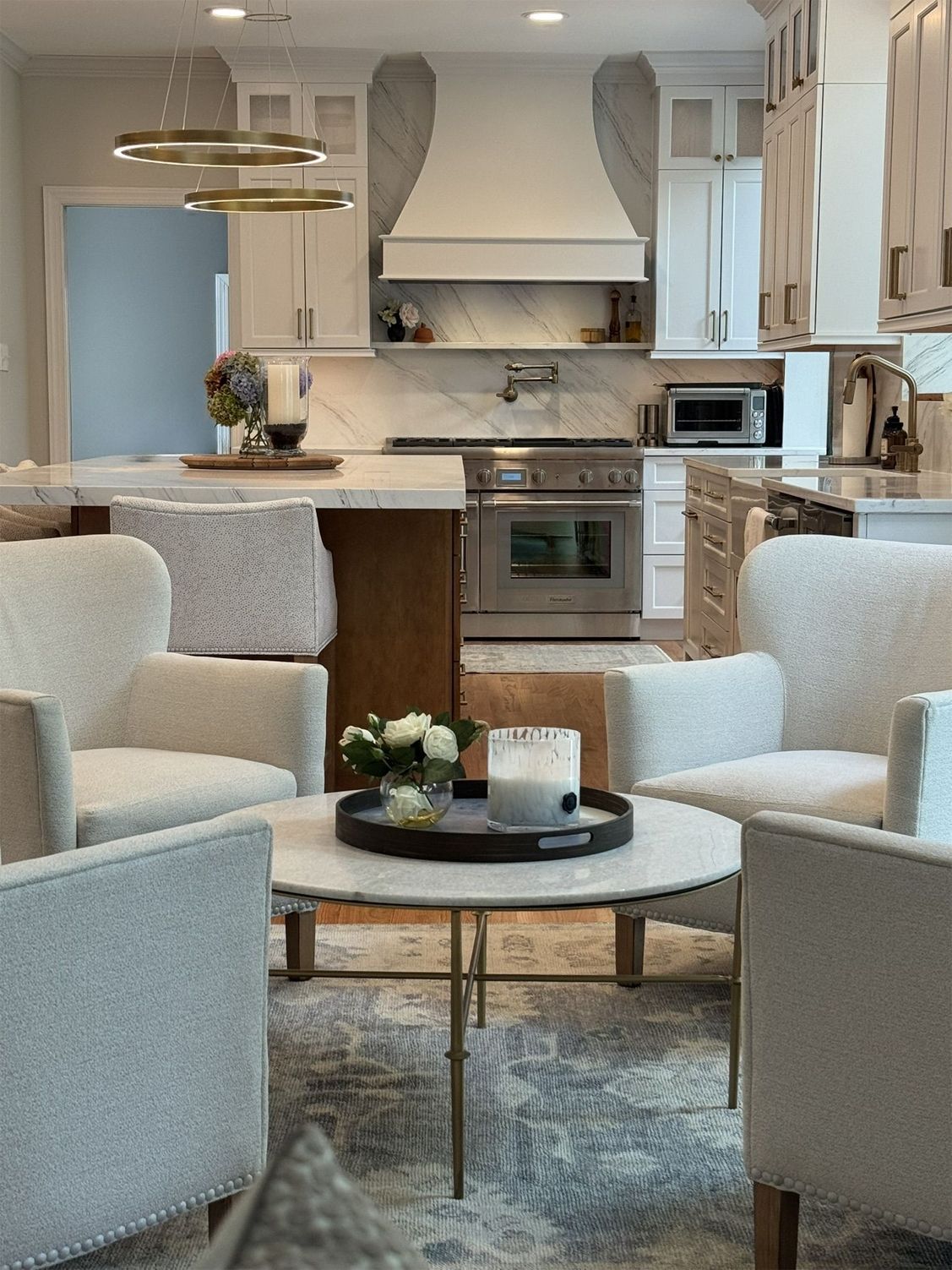 Cozy kitchen with marble countertops, stainless steel appliances, and seating area with four armchairs around a coffee table.