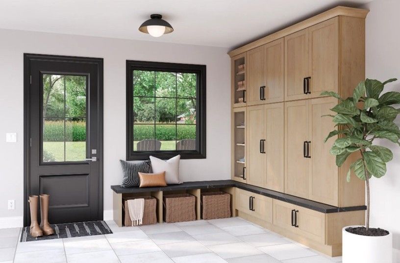 Mudroom with wooden storage cabinets, a bench, and a black door.
