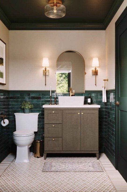 Bathroom with green brick tile, gray vanity, arched mirror, and brass accents.