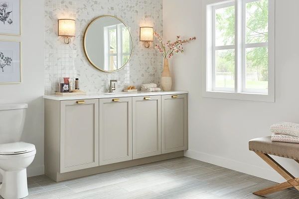 Bathroom vanity with mirror, sconces, and neutral cabinets; a window provides natural light.