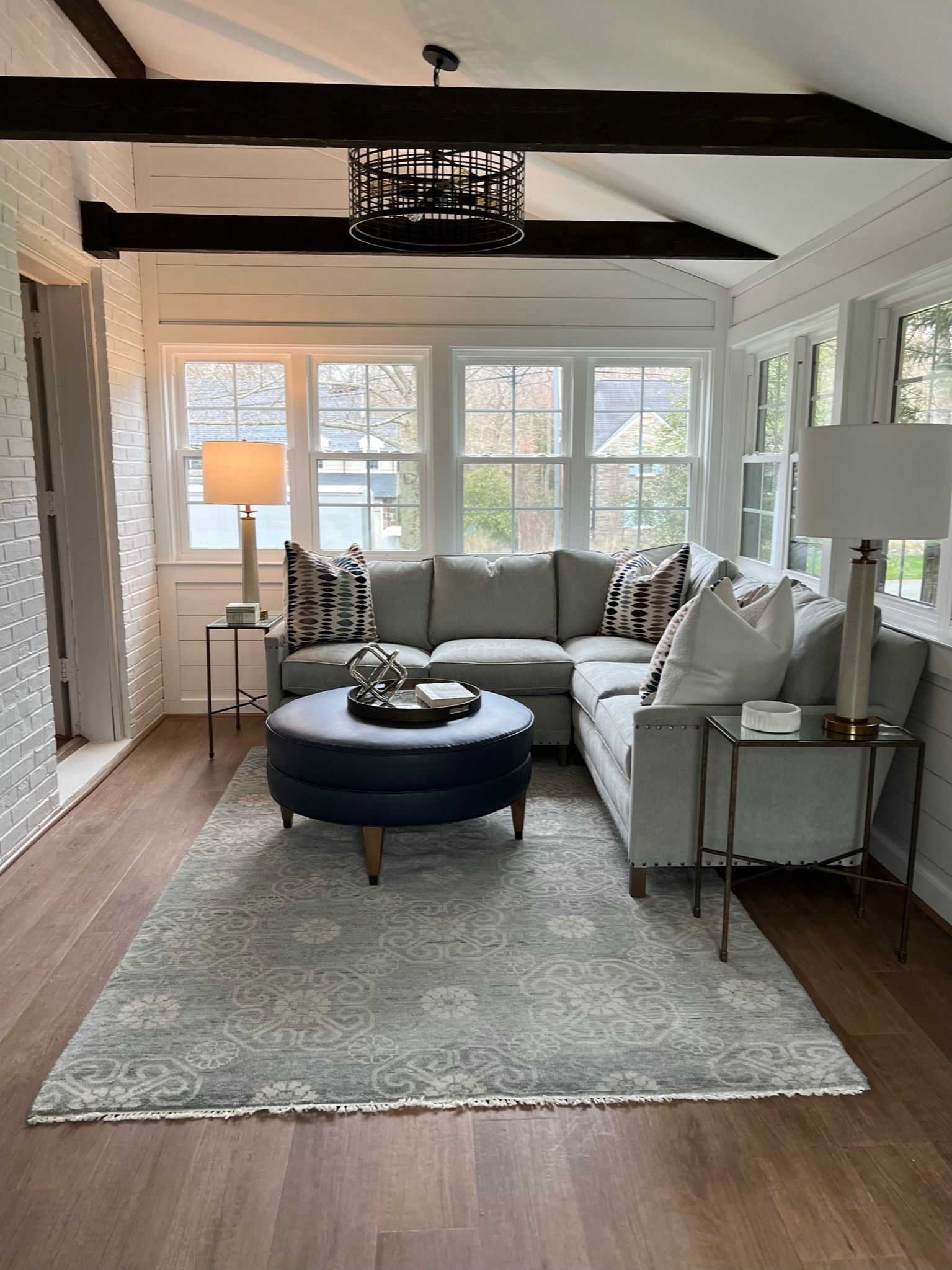 A living room with a couch , ottoman , lamps and a rug.