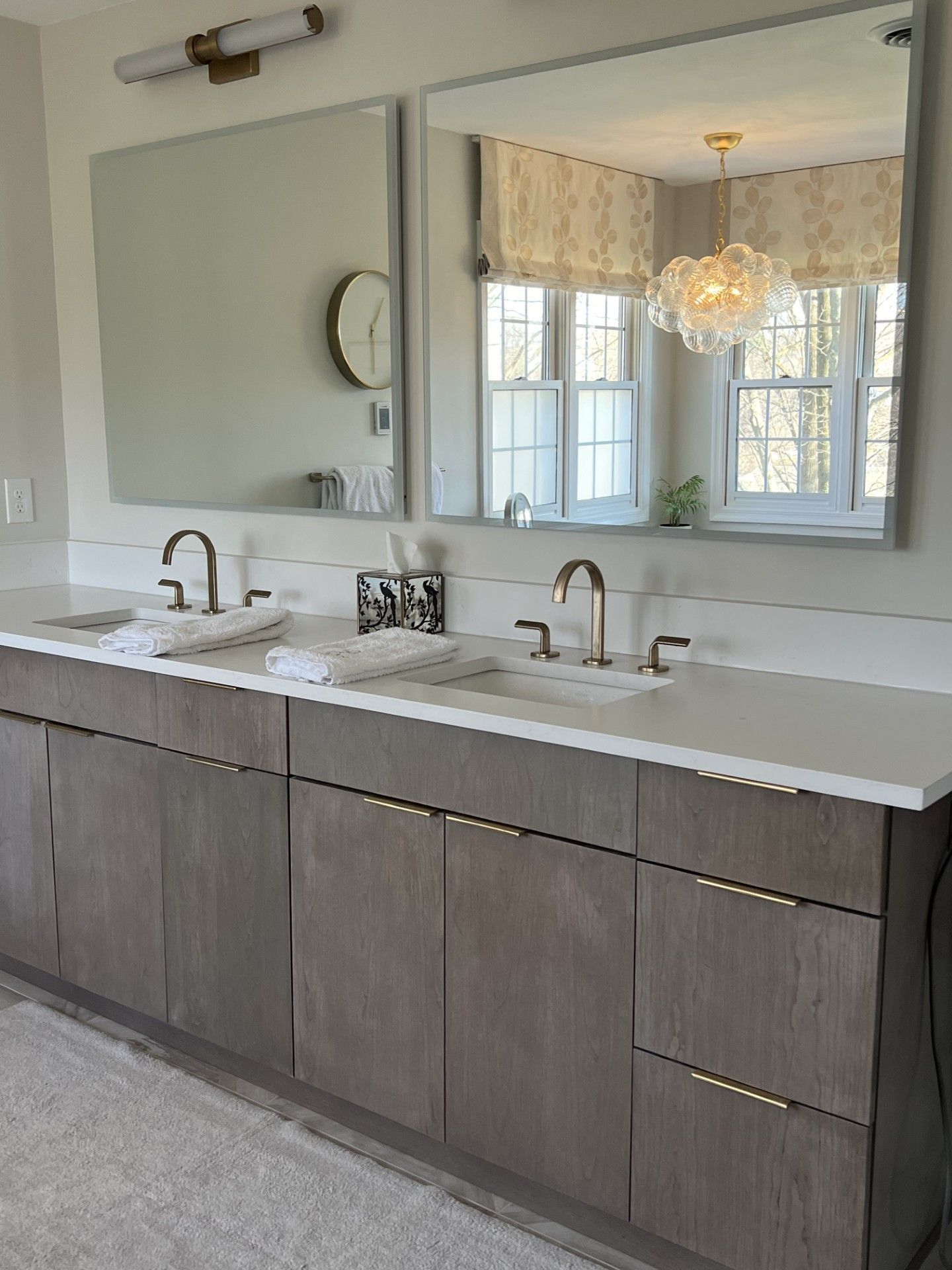 Modern bathroom with double vanity, large mirrors, and gray cabinetry.