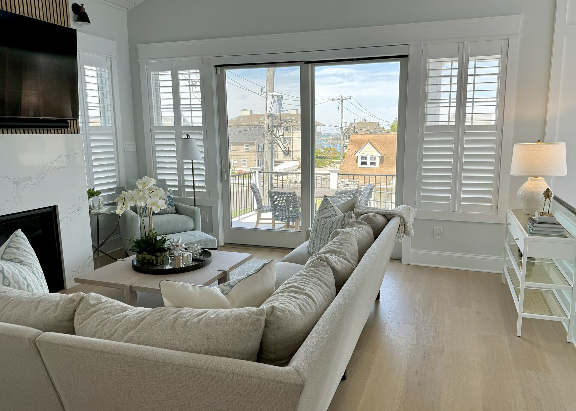 A living room with a couch , fireplace , television and shutters.
