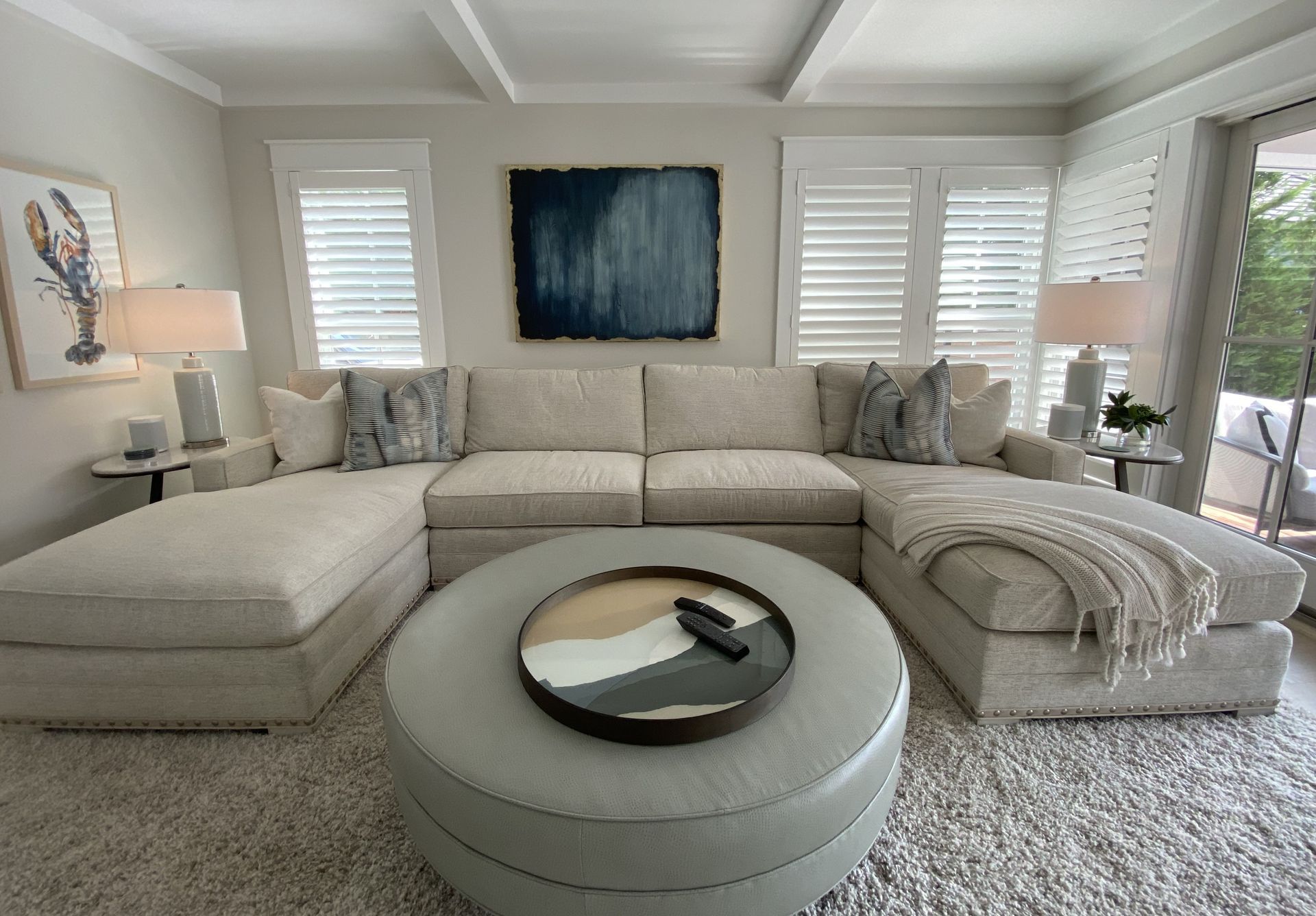 A living room with a large sectional couch and a round coffee table