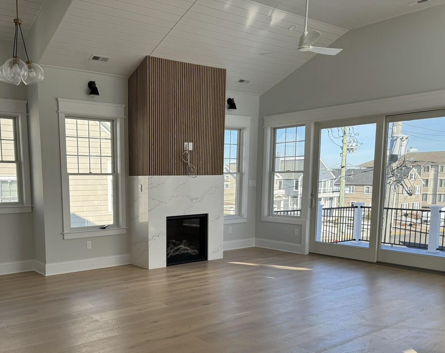 An empty living room with a fireplace and lots of windows.