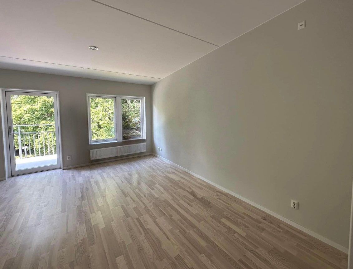 An empty living room with hardwood floors and a balcony.