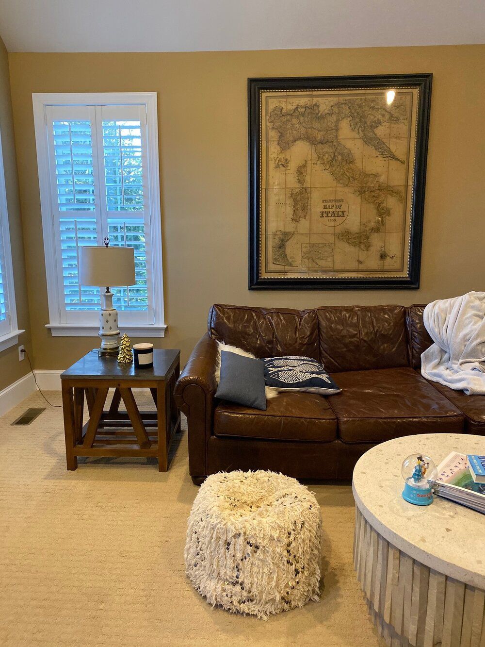 A living room with a couch, coffee table, and a map on the wall.