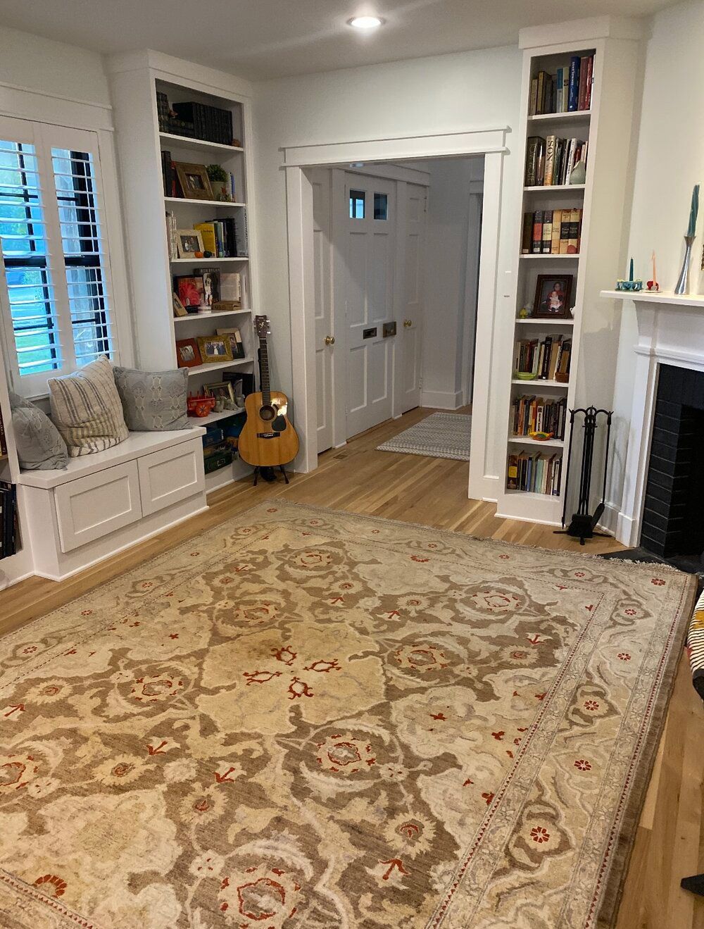 A living room with a large rug and a fireplace.