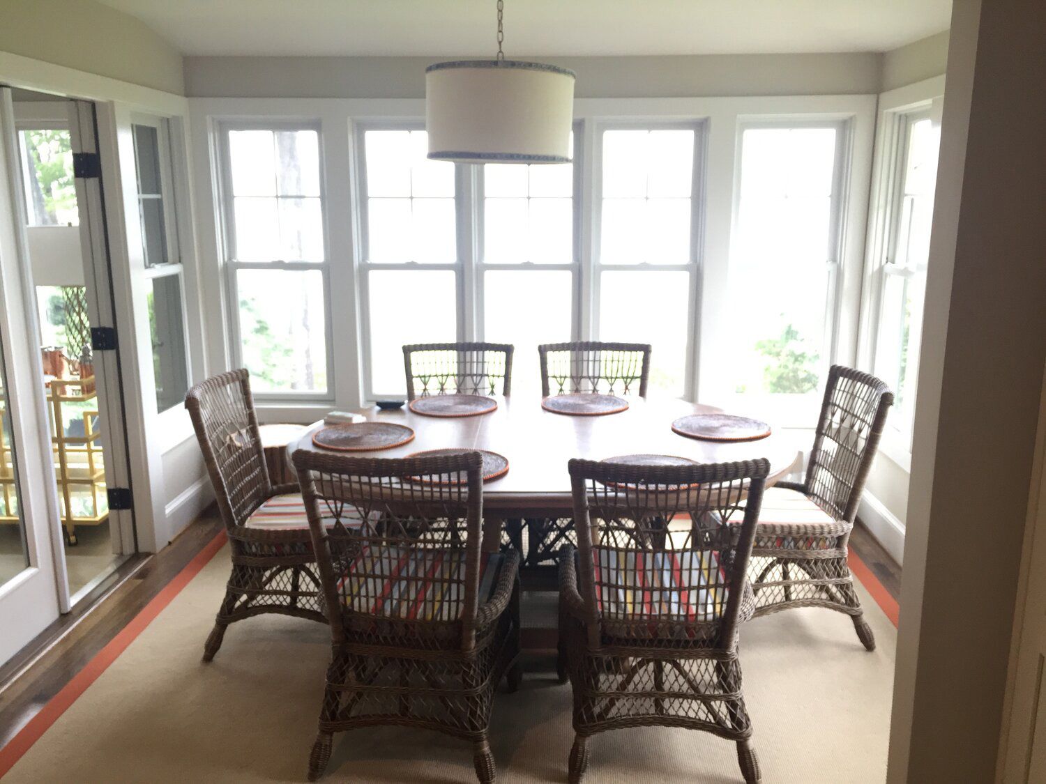 A dining room with a table and chairs and lots of windows
