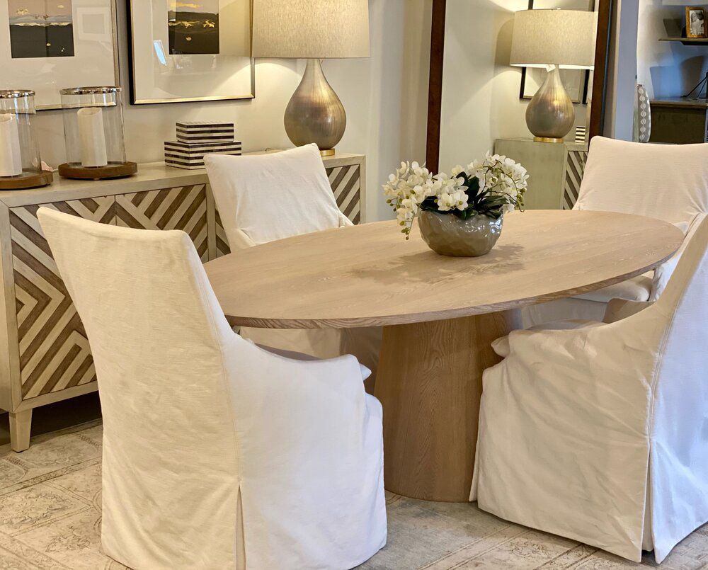 A dining room with a table and chairs with white covers