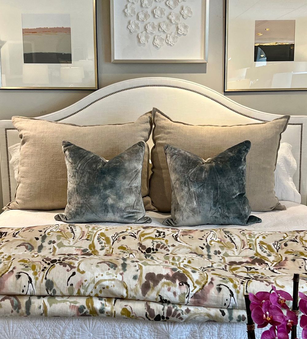 A bed with a floral comforter and pillows on it.