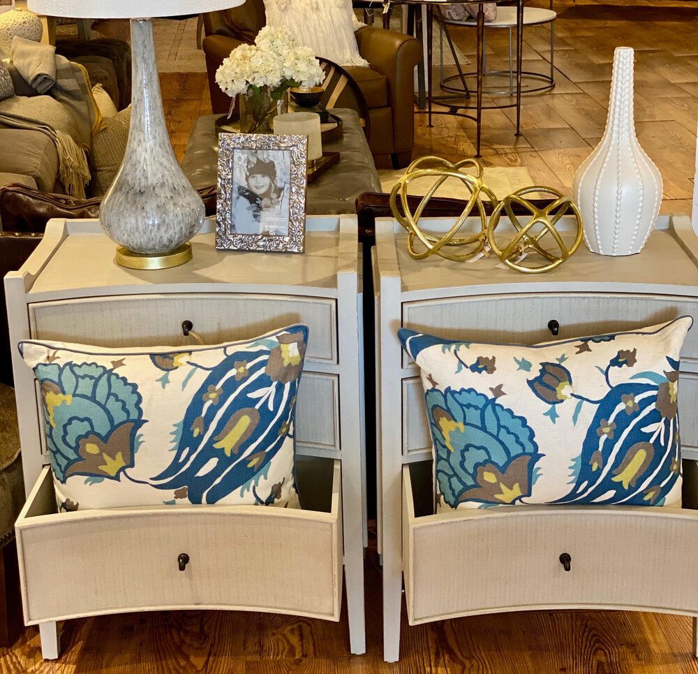 Two nightstands with pillows and lamps on them in a living room