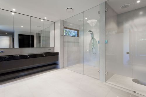 Modern bathroom with glass shower, vanity, and white tiled floor