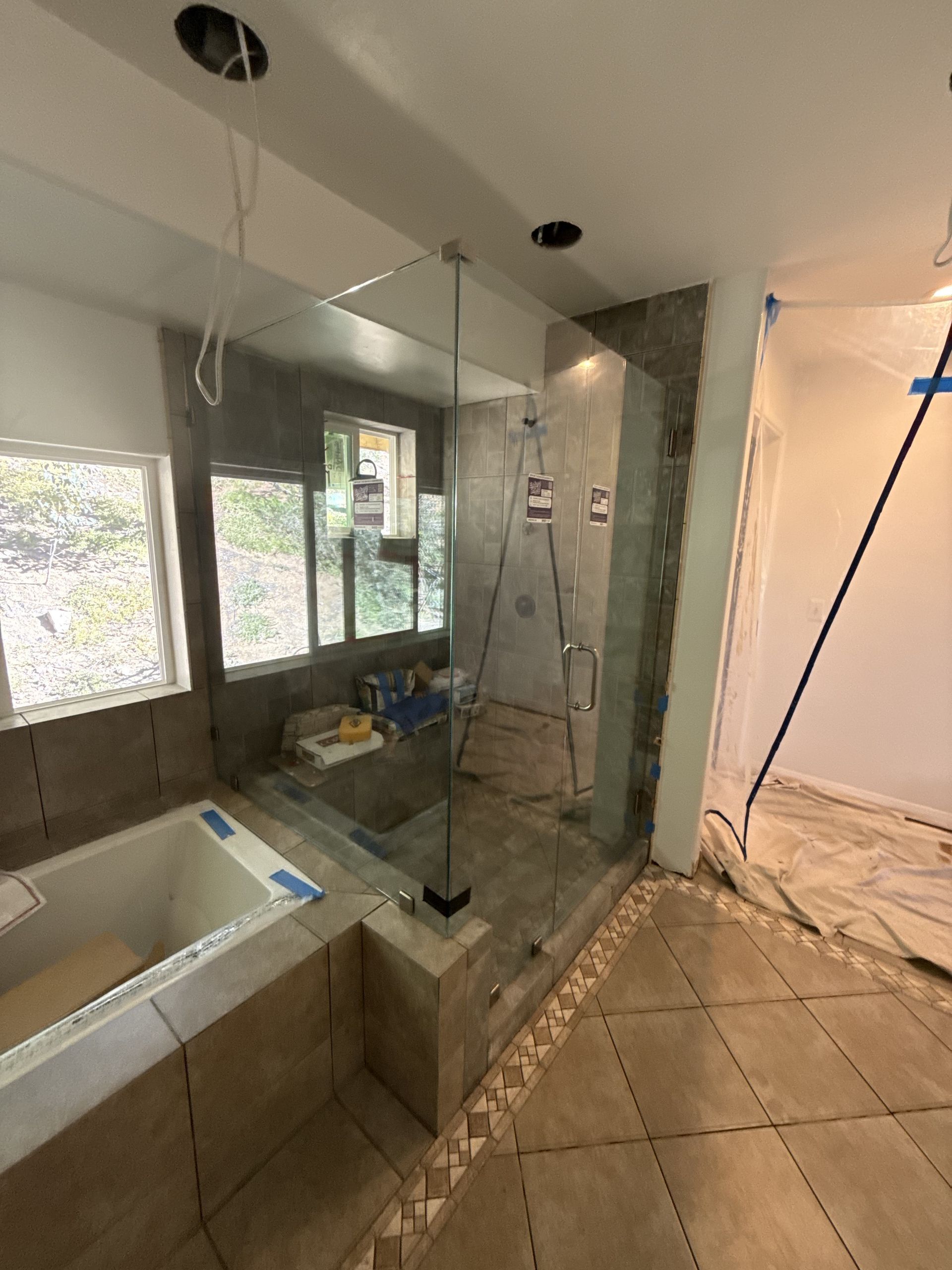 Partially renovated bathroom with tiled floor, sink, mirror, and ladder near a shower area
