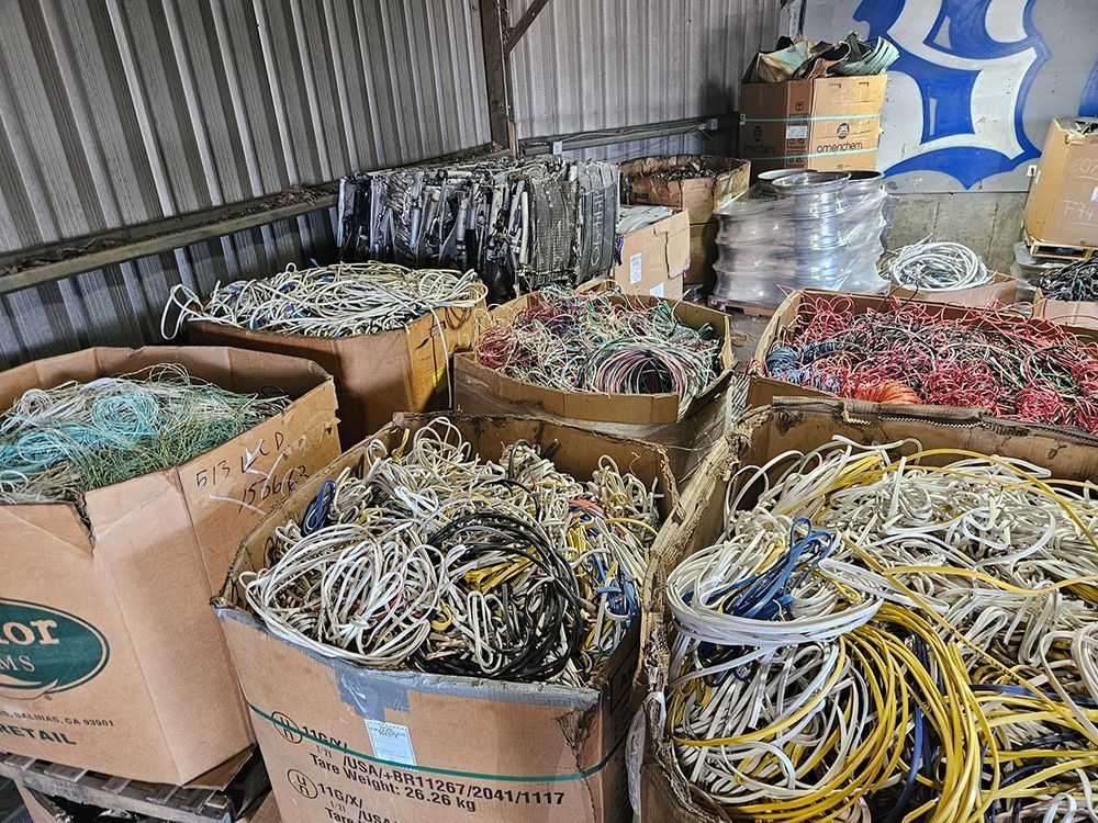 Piles of colorful electrical wires and cables fill cardboard boxes in a storage area.