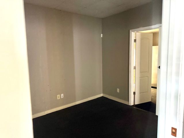 Empty room with dark floor, gray walls, and an open door to a hallway.