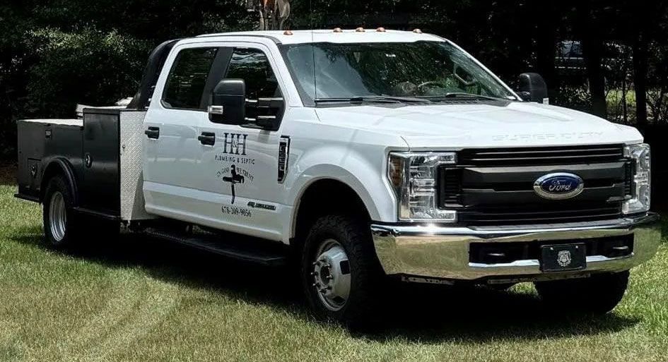 White Ford F-350 service truck with black service body parked on grass.