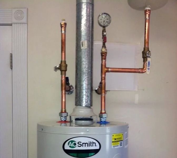 A.O. Smith water heater with copper pipes, a flue, and a gauge against a light-colored wall.