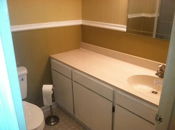 Small bathroom with toilet, sink, and beige cabinets and walls.