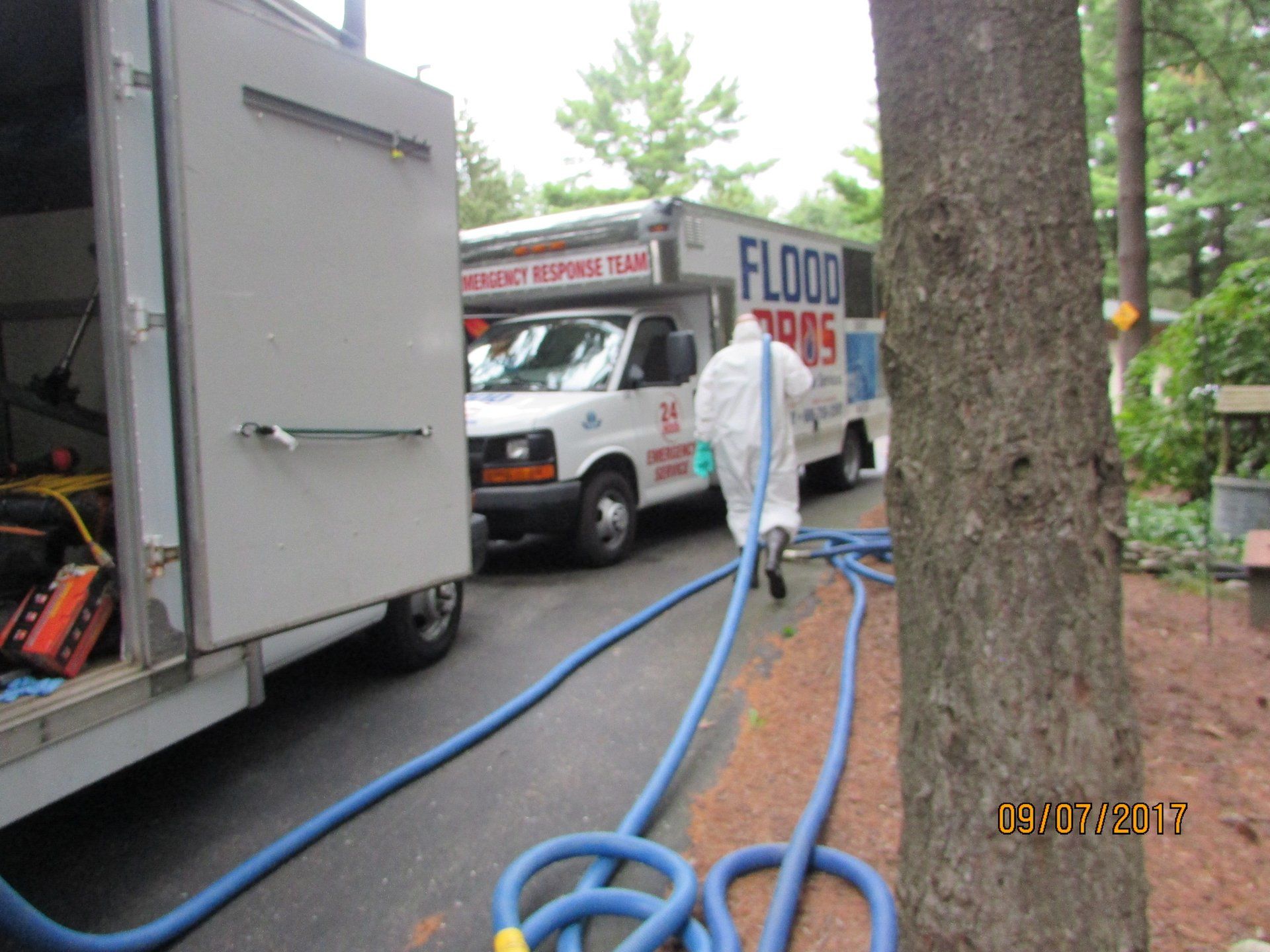 A person in protective gear unrolls a blue hose from a truck marked 