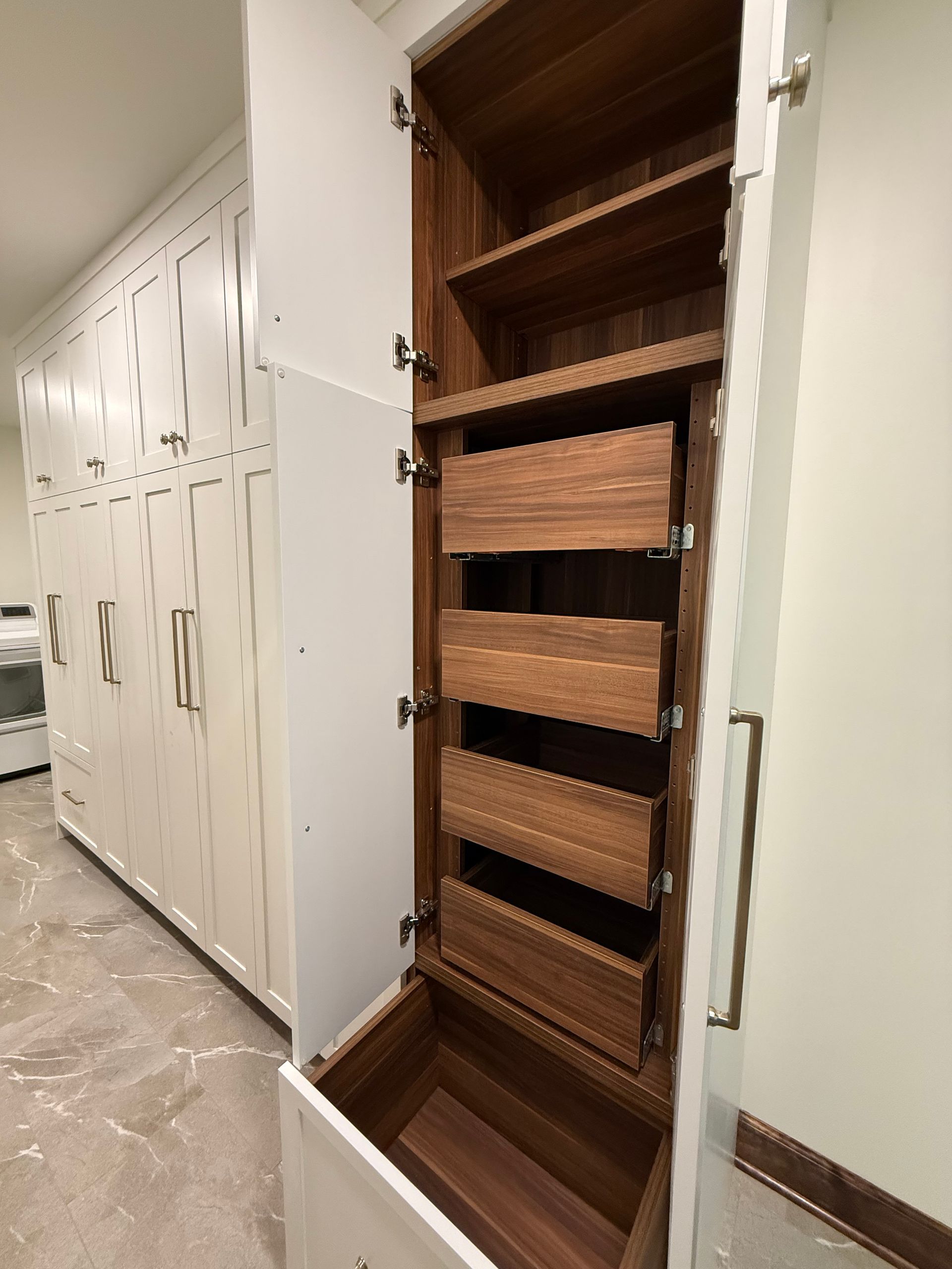 Open cabinet with pull-out wooden shelves beside white hallway lockers