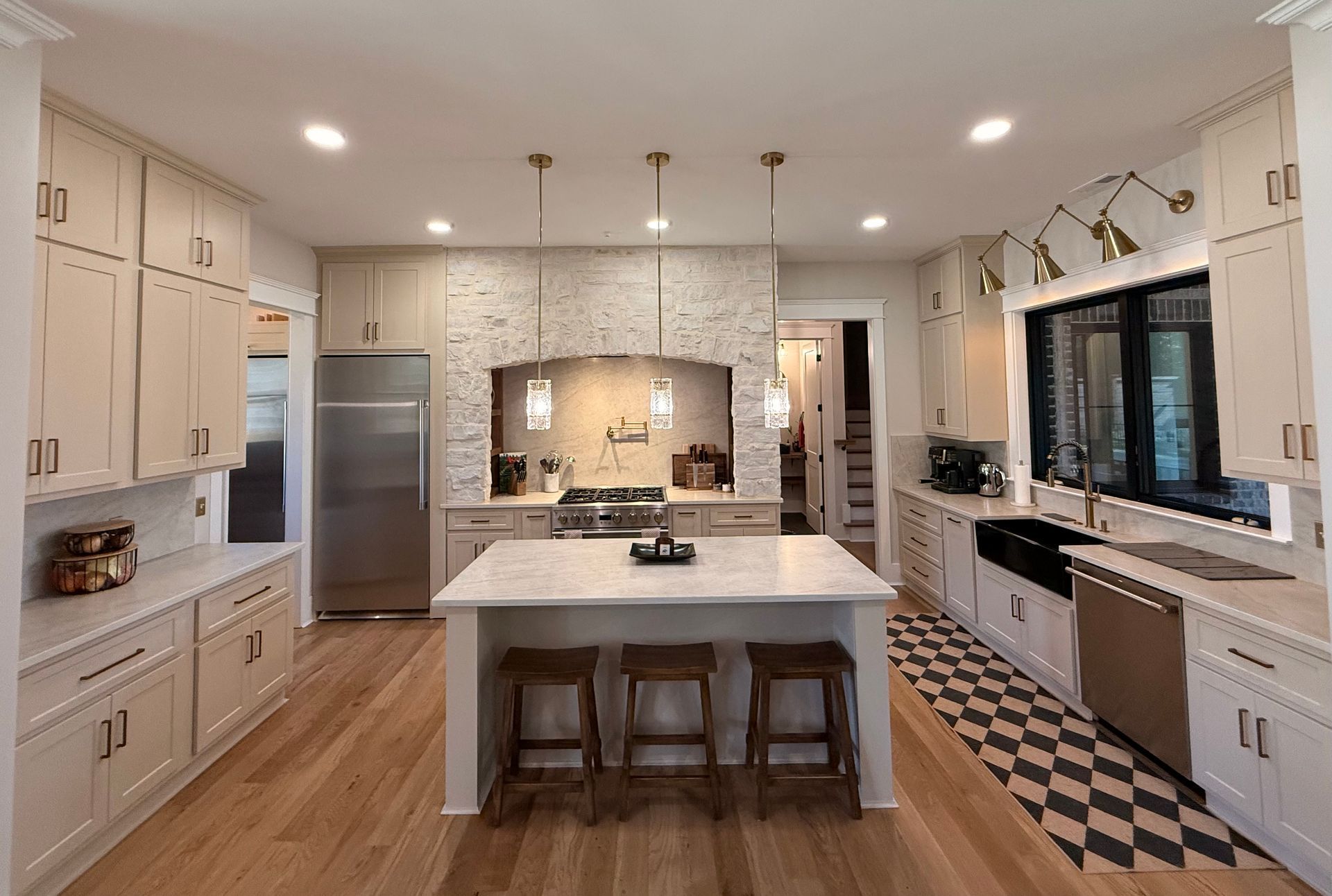 Bright modern kitchen with white cabinets, island, pendant lights, and black-and-white tile floor