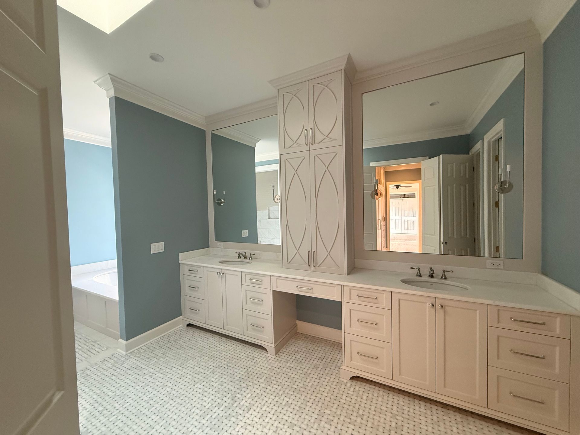 Blue-and-white bathroom vanity with double sinks, large mirror, and patterned tile floor