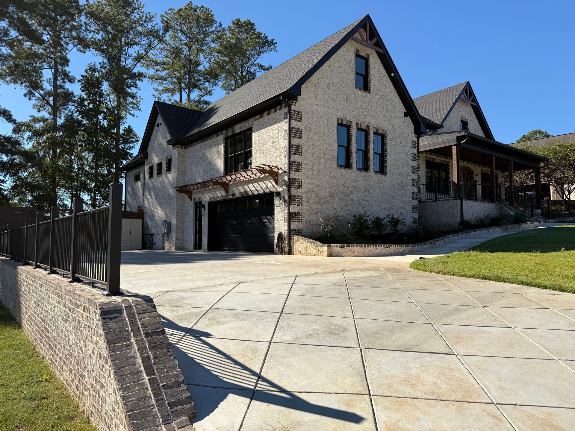 Stone house with a garage and large driveway on a sunny wooded hillside