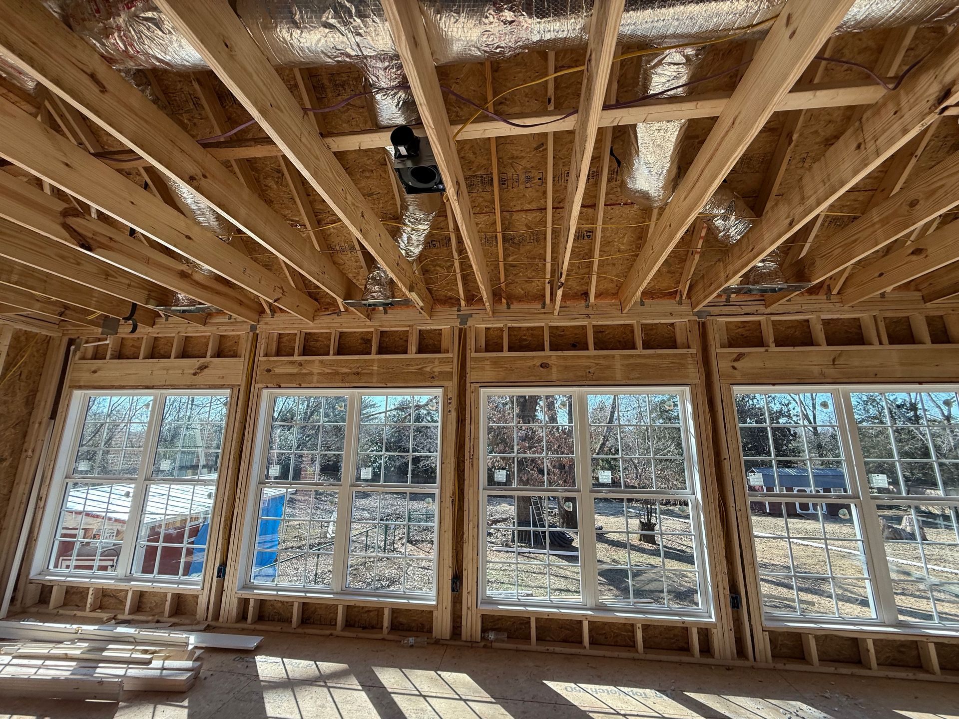 Interior view of a building under construction, showing wooden framework with large windows.