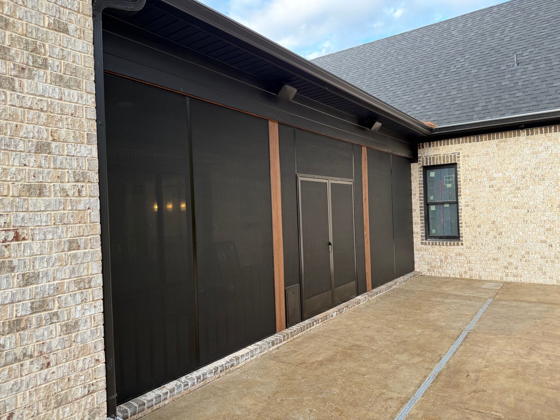 Exterior of a brick building with dark material covering a side wall, partially covering a doorway.