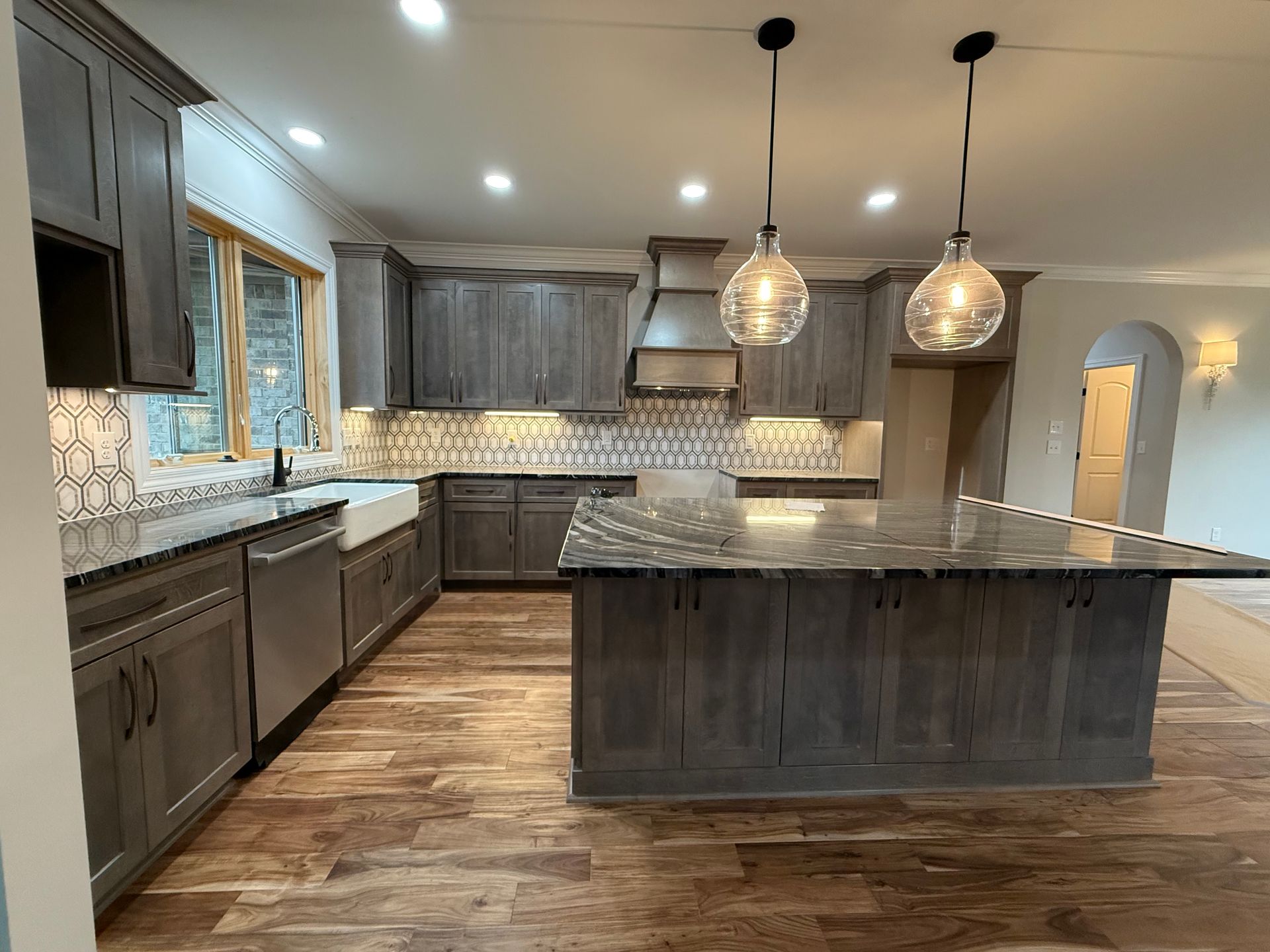Modern kitchen with gray cabinets, granite island, pendant lights, and wood flooring
