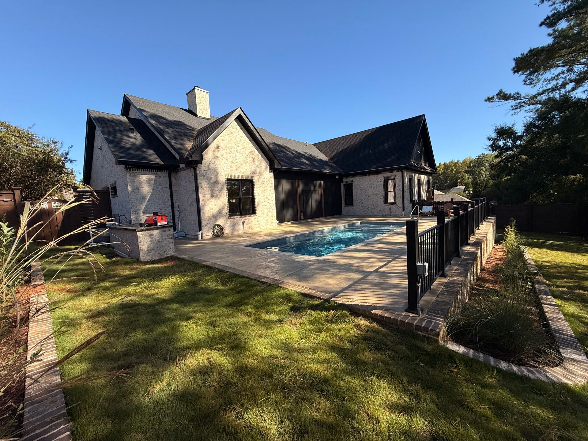 Stone house with a swimming pool and patio in a sunny yard