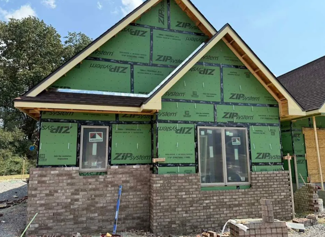 New house construction with brickwork and green sheathing.