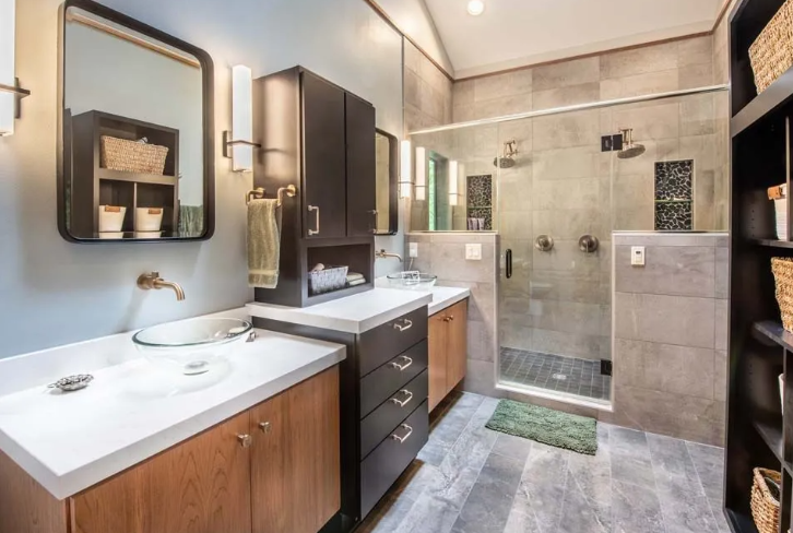 Modern bathroom with gray tile shower, wood cabinets, and white countertops.