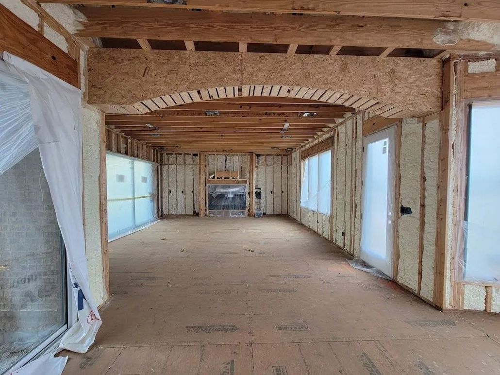 Interior of a building under construction, showing wooden frame, insulation, and a fireplace.