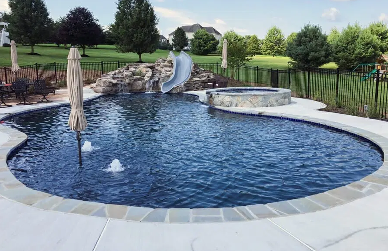 A large swimming pool with a water slide in the backyard.